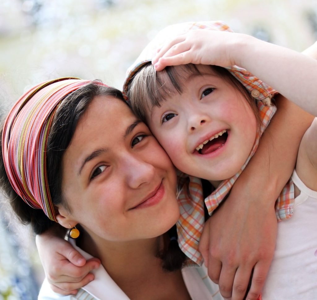 Young girl with down syndrome smiling and hugging friend