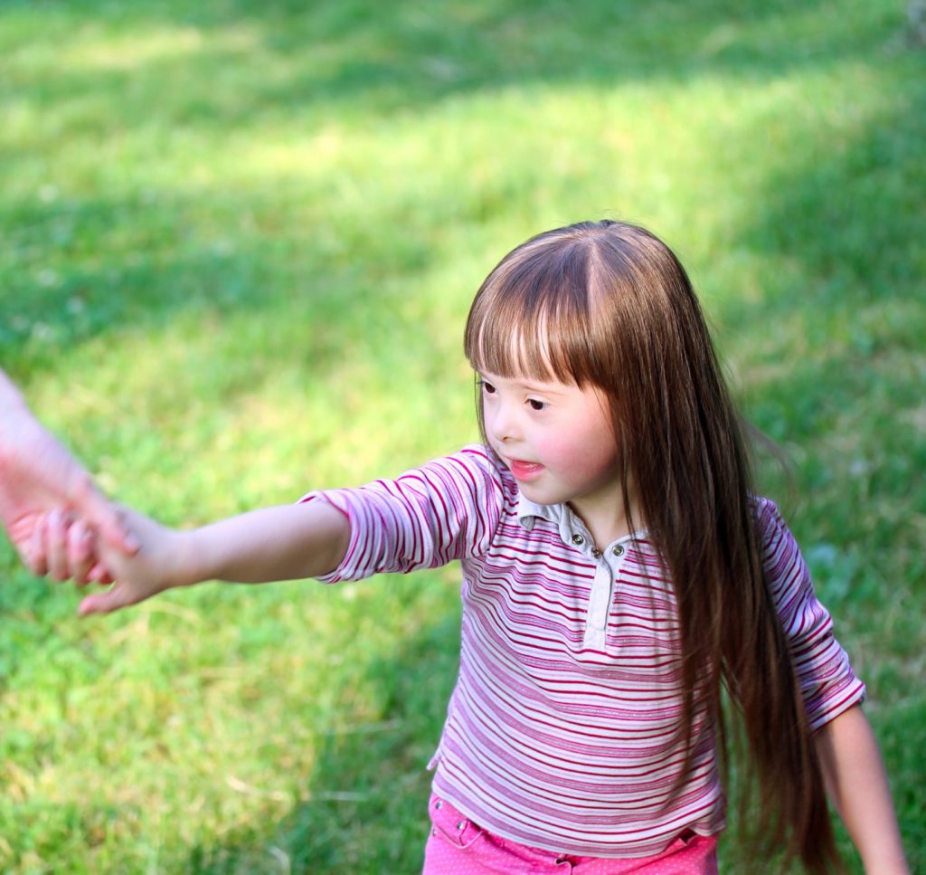Young girl with down syndrome holding hands with adult